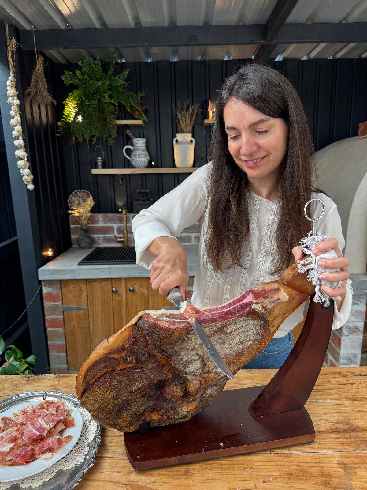 Snezana carving pršut on a wooden stand