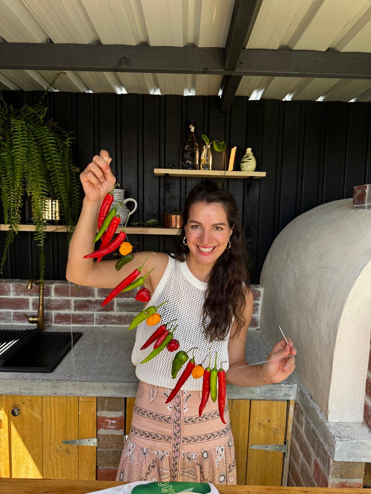 Snezana hanging a string of chillies to dry in her outdoor kitchen