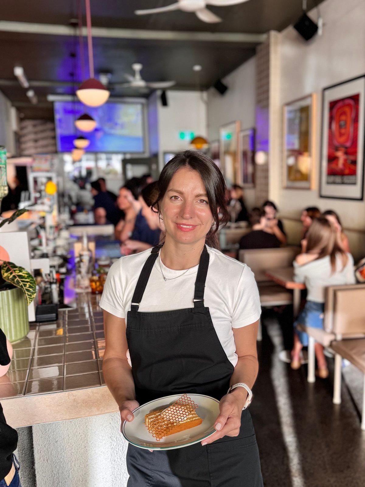 Snezana serving her honey cake in a full dining room during the Eat Pierogi Make Love pop-up